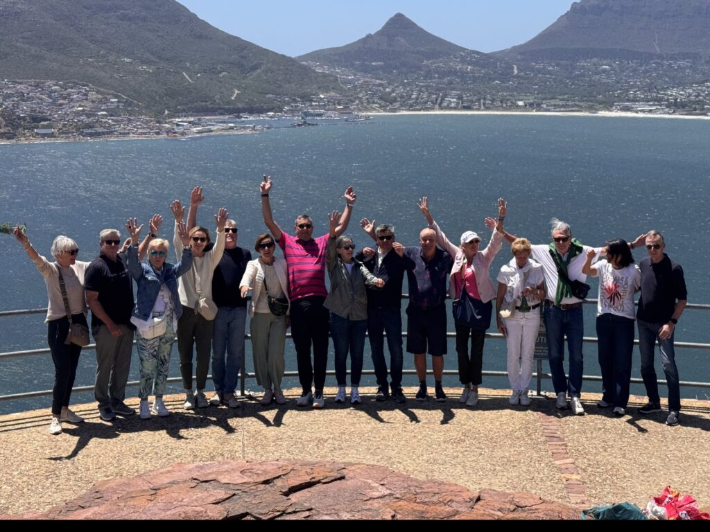 Reisegruppe winkt am Aussichtspunkt Chapman’s Peak, dahinter Hout Bay